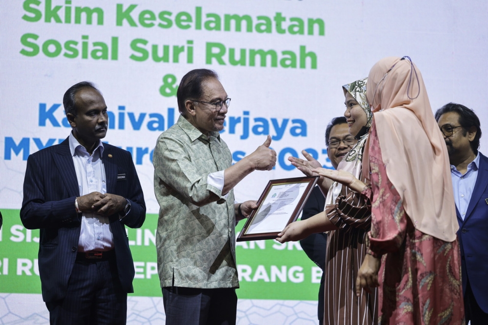 Prime Minister Datuk Seri Anwar Ibrahim (second left) presenting a certificate to Athira Nasuha Azman who was accompanied by her mother at the SKSSR Launch Ceremony and MYFutureJobs Career Carnival 2023 at the Kuala Lumpur Convention Center February 11, 2023. — Bernama pic