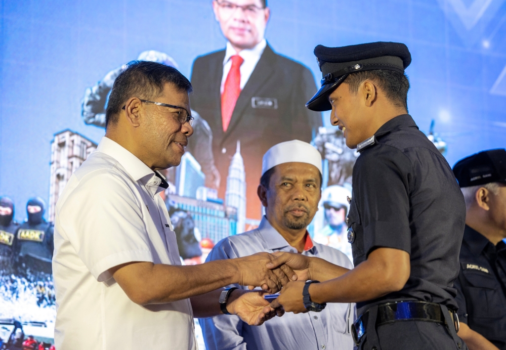 Home Minister Datuk Seri Saifuddin Nasution Ismail (left) handing over an identity card to one of the members of the Royal Malaysian Police in conjunction with the Ministry of Home Affairs (KDN) Civil 2023 Program at the Jajahan Unity Complex, Machang, February 18, 2023. — Bernama pic