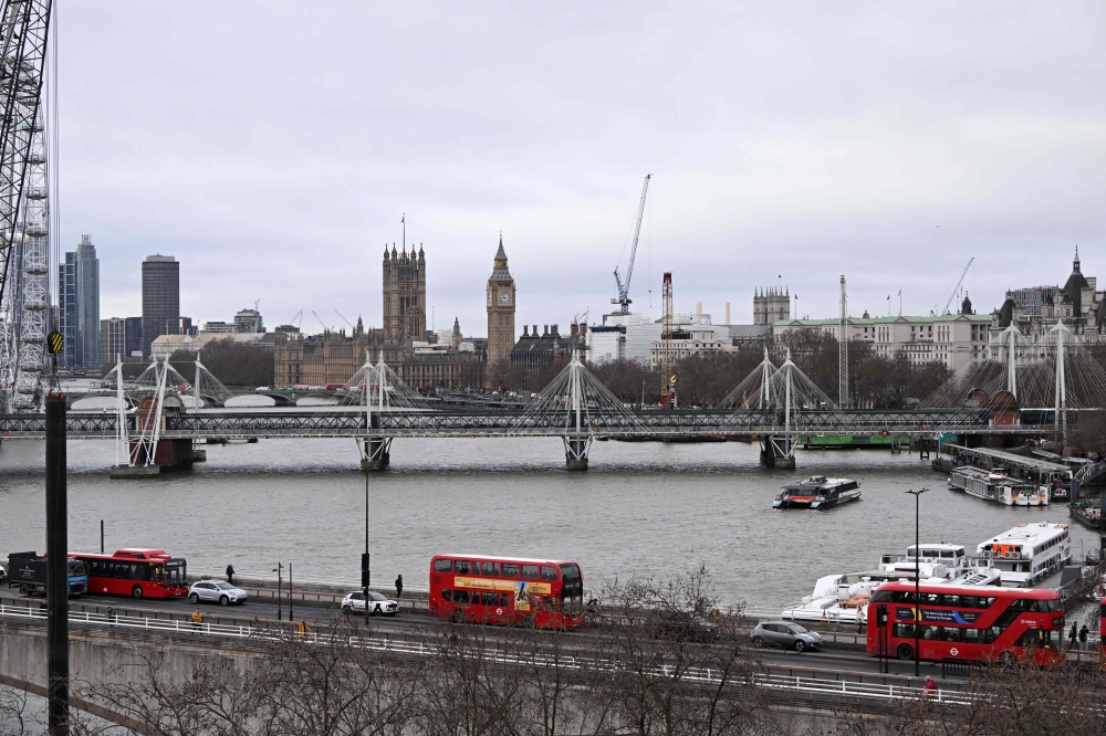 Three red London buses cross Waterloo Bridge over The River Thames with the Palace of Westminster and Elizabeth Tower seen behind, viewed from Somerset House in London on February 16, 2023. — Reuters pic