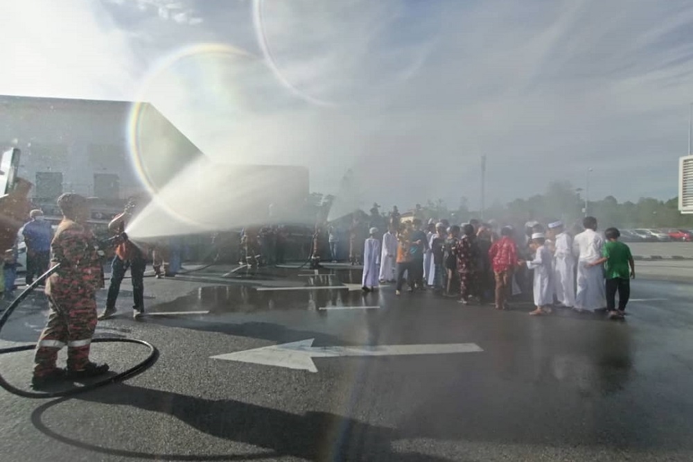 A firefighter hoses down the boys at the start of the ‘berkhatan’ event at KPJ Kuching Specialist Hospital. — Henrietta Liza/Borneo Post pic