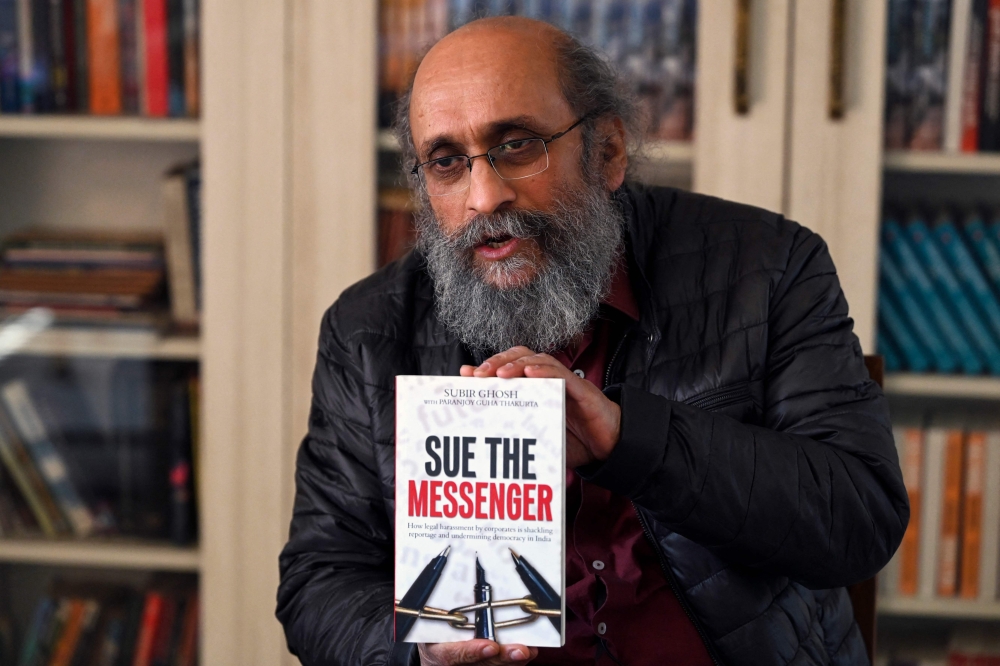 In this picture taken on on February 8, 2023, Independent Indian journalist Paranjoy Guha Thakurta holds a copy of the book ‘Sue the Messenger’ by authors Paranjoy Guha Thakurta and Subir Ghosh, as he speaks with AFP during an interview at his residence in Gurugram. — AFP pic