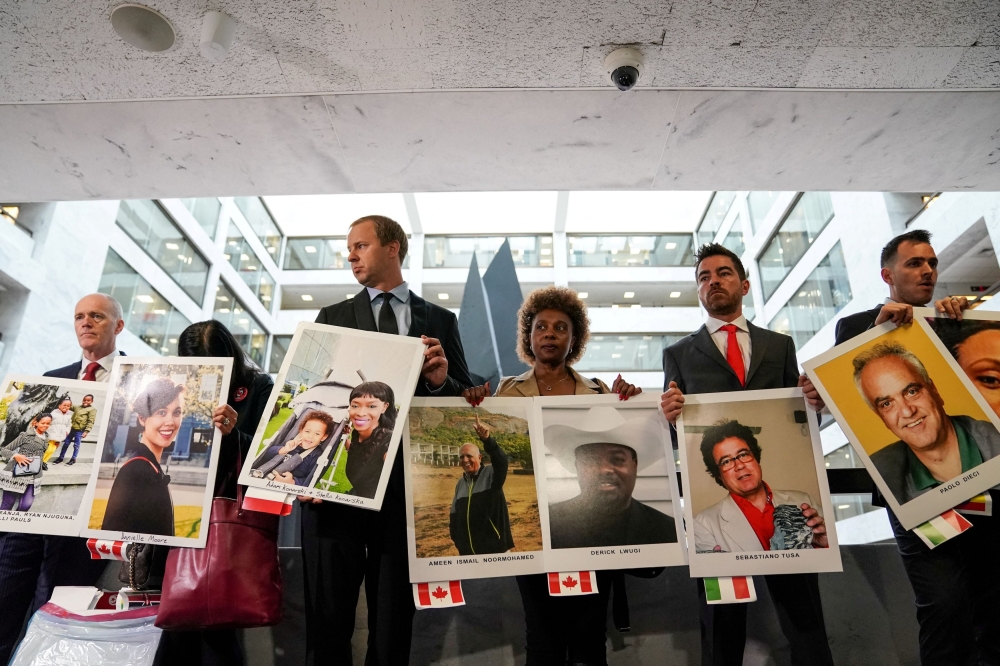 Family members hold photographs of Boeing 737 MAX crash victims lost in two deadly 737 MAX crashes that killed 346 people as they arrive for Boeing CEO Dennis Muilenburg's testimony before a Senate Commerce, Science and Transportation Committee hearing on 