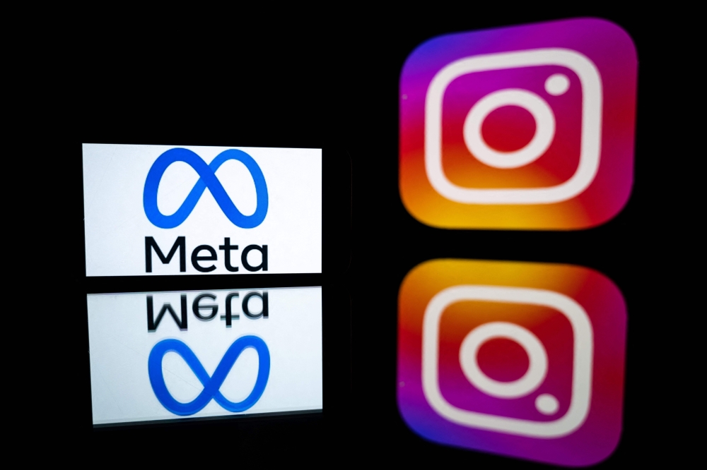 This file illustration photo taken on January 12, 2023 in Toulouse, southwestern France, shows a smartphone and a computer screen displaying the logos of Instagram app and its parent company Meta.— AFP pic
