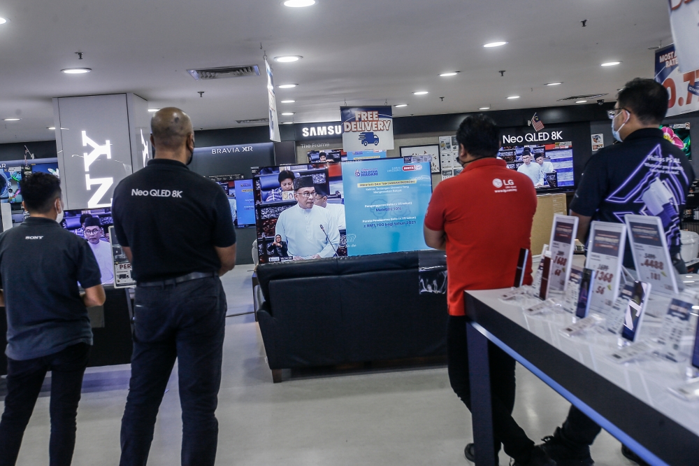 Staff in an electrical shop in Setapak watching on television as Malaysian Prime Minister Datuk Seri Anwar Ibrahim presented the 2023 budget in Parliament, Kuala Lumpur, February 24, 2023. — Picture by Hari Anggara