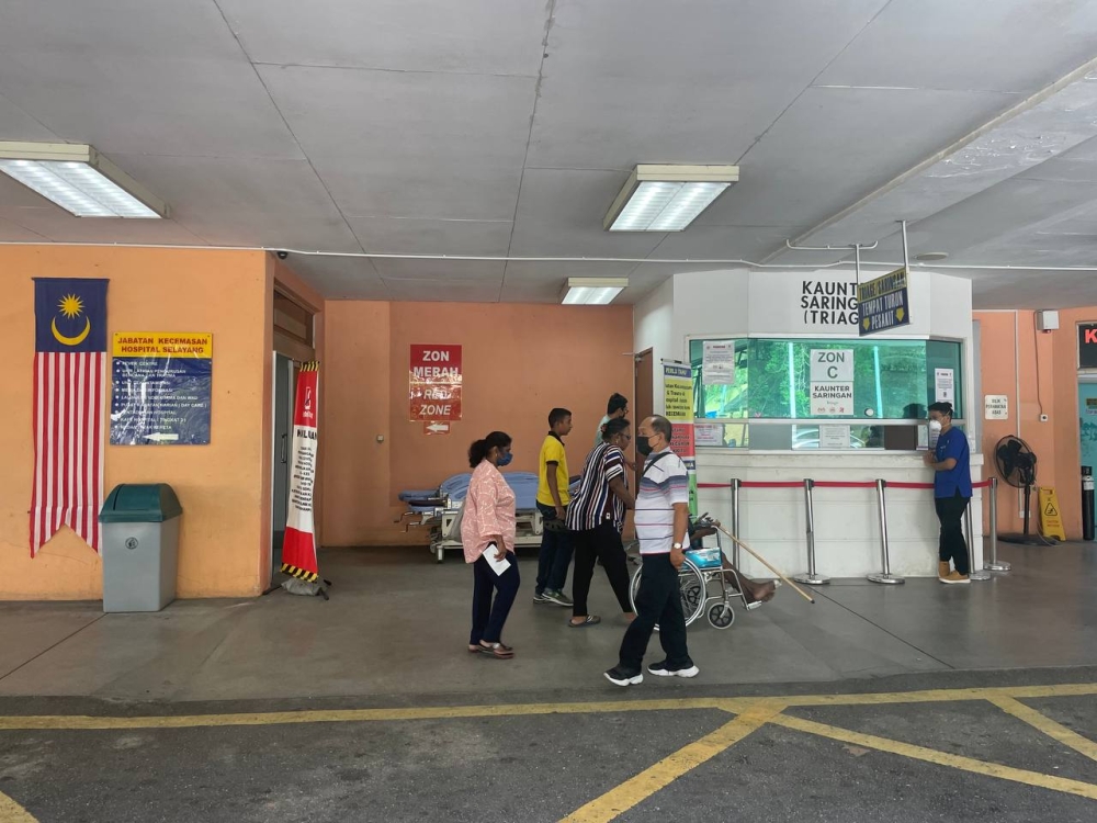 People are seen walking near the screening counter at the entrance of Selayang Hospital's emergency department in the late afternoon hours on February 16, 2023. — Picture by Rex Tan