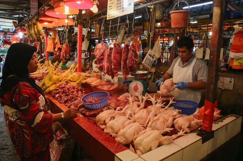 A woman shop for chicken and beef at wet market in Kuala Lumpur December 23, 2019. — Picture by Yusof Mat Isa