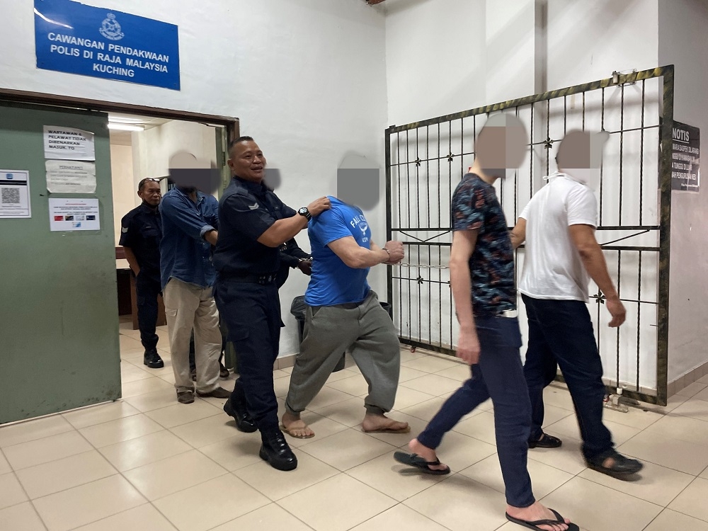 The Algerian (third right) is led from the court lockup to be sent to Puncak Borneo Prison to begin his sentence. — Borneo Post Online pic
