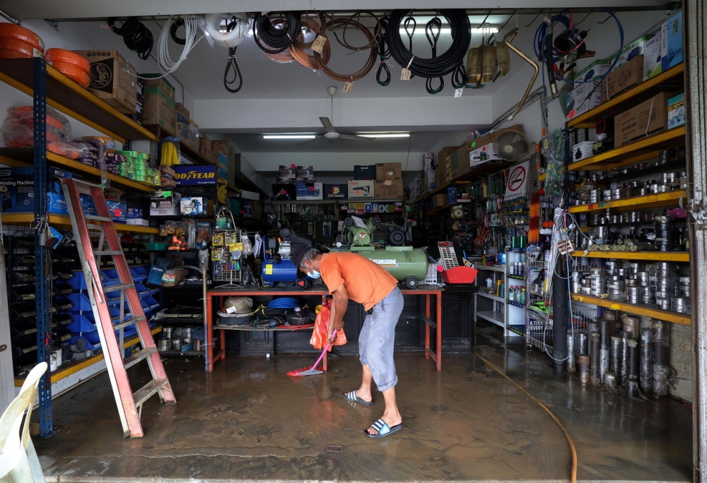 An employee of a shop selling vehicle equipment cleans the shop after the water began to recede as a result of the flood on Jalan Kota Kecil 1, in Bandar Kota Tinggi, March 1, 2022. — Bernama pic