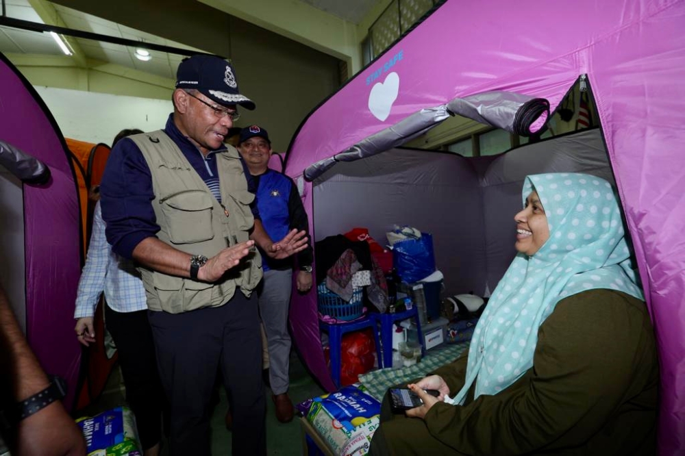 Home Minister Datuk Seri Saifuddin Nasution Ismail with a flood victim during his visit to a temporary relief centre at the Kampung Melayu Kluang community hall in Kluang March 3, 2023 — Picture by Ben Tan