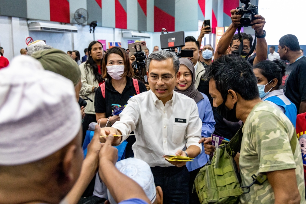 Communications and Digital Minister Fahmi Fadzil distributes mobile phone sim cards to residents during the Mobile Internet Unity Package Pre-launch Ceremony at Perumahan Awam Desa Rejang in Setapak February 28, 2023. ― Picture by Firdaus Latif