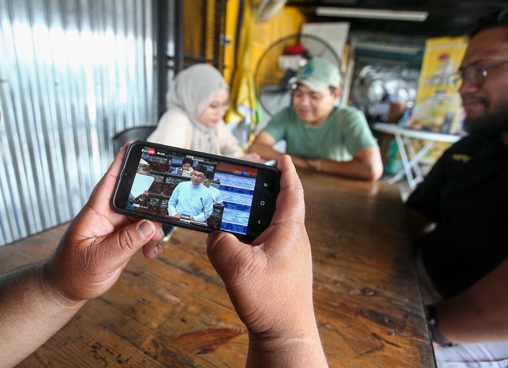Malaysians watch the live feed of Budget 2023 via their smart phones, which was tabled by the Prime Minister Datuk Seri Anwar Ibrahim. — Picture by Farhan Najib