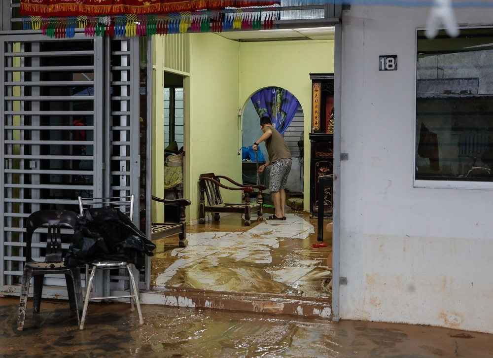 A Bekok resident is seen cleaning his house after the floods in Segamat March 5, 2023. — Bernama pic