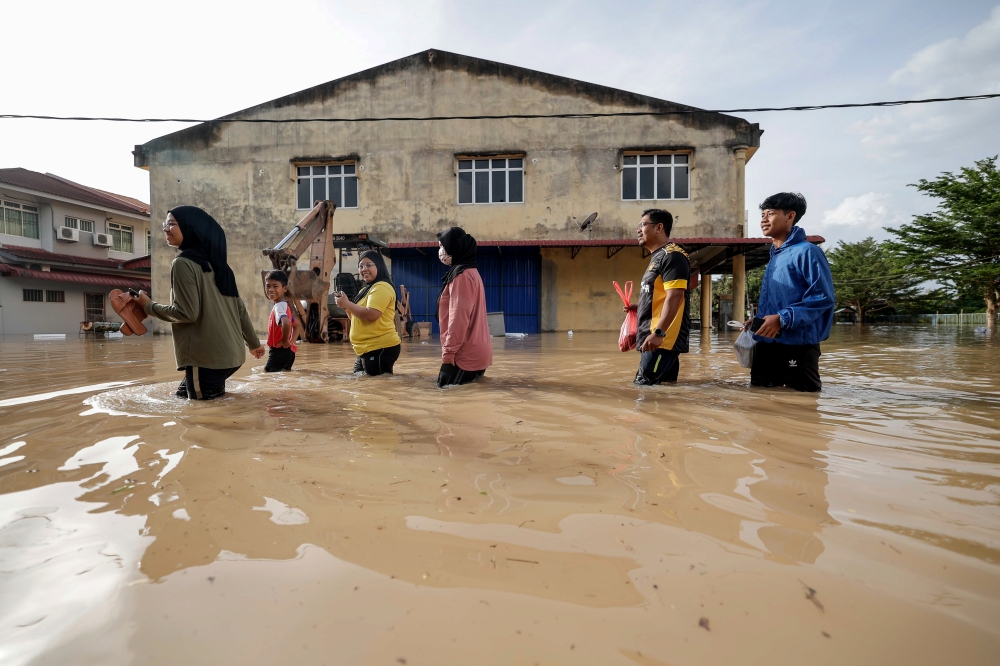 Residents walk through floodwaters at Seri Medan in Batu Pahat March 5, 2023. — Bernama pic