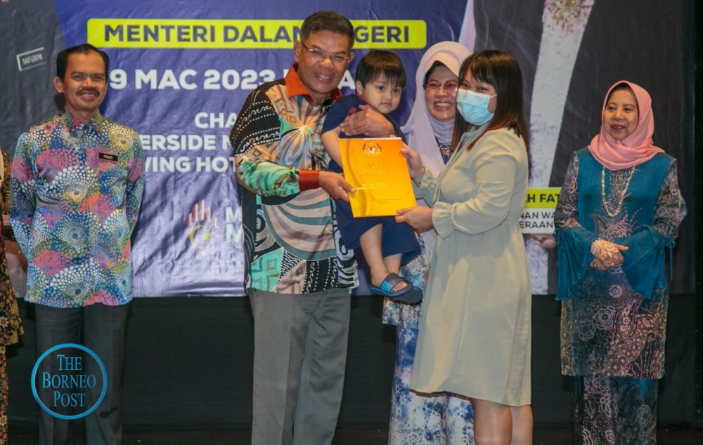 Saifuddin presents a citizenship approval letter to a successful applicant. At third right is Women, Children and Community Wellbeing Development Minister Datuk Seri Fatimah Abdullah. ― Picture by Muhammad Rais Sanusi