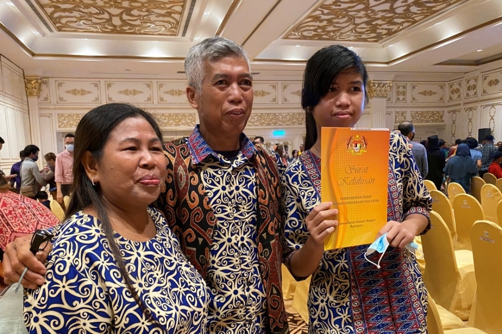 Katrina (right) shows her citizenship approval letter file accompanied by parents Draup and Flora Sangkoi. — Borneo Post Online pic