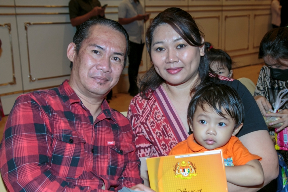 Rebecca and her husband Hermon Maurice with their son Xavier at the presentation of citizenship approval letter ceremony. — Borneo Post Online pic