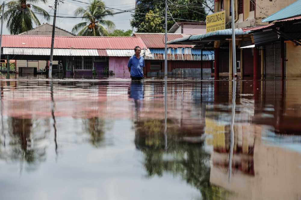 A man wades in flood water at Parit Sulong town in Johor March 9, 2023. — Bernama pic
