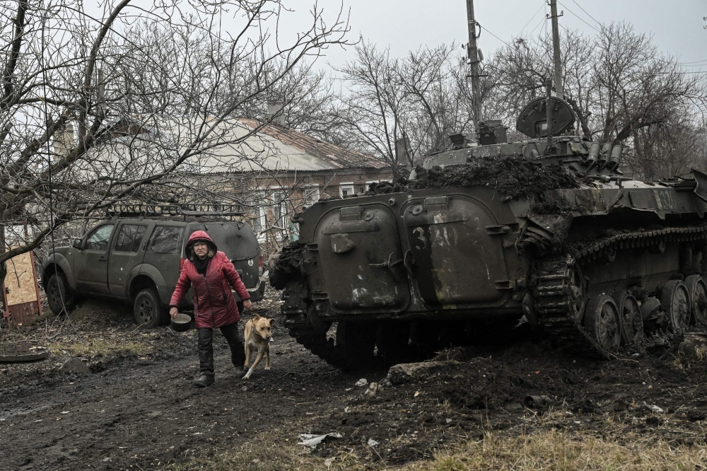 A woman walks past a destroyed BMP-2 tank after a shelling in the village of Chasiv Yar on March 11, 2023 amid the Russian invasion of Ukraine. — AFP pic