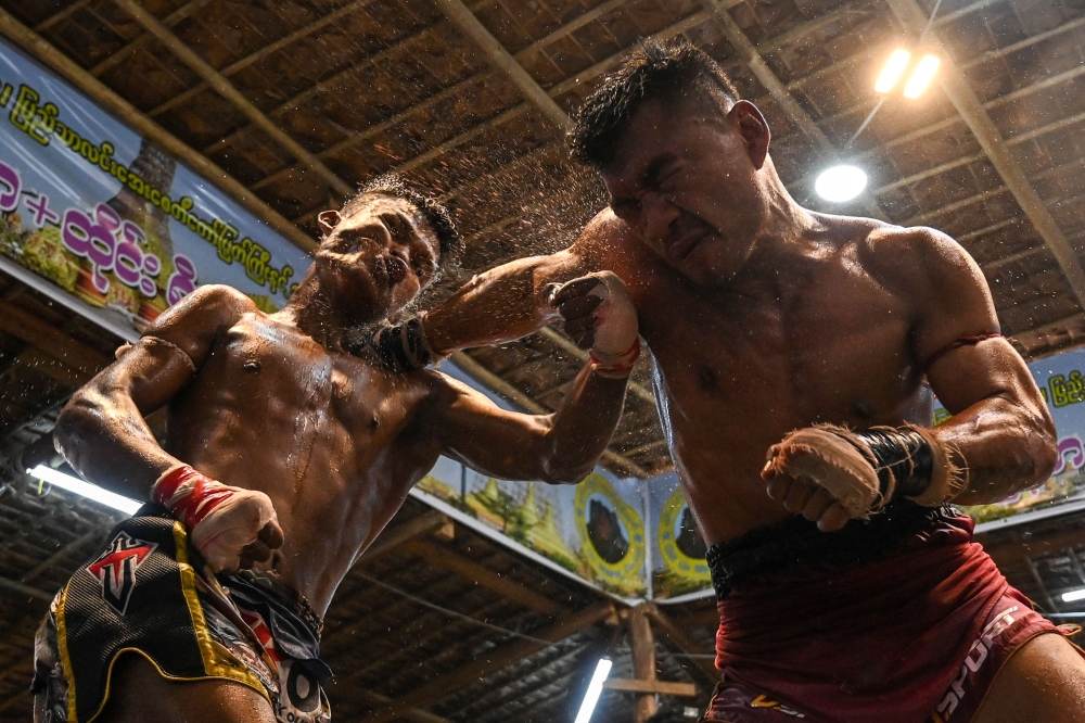 This photo taken on March 5, 2023 show fighters Htun Linn Aung (left) and Nay Htoo Htoo (right) competing in the ring during a traditional Myanmar boxing Lethwei tournament at Pyi Thar Lin Aye pagoda in Hlaingbwe township in Karen state. — AFP pic