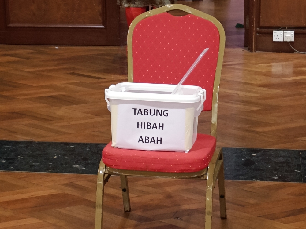 A collection box for Muhyiddin's legal fees can be seen placed at the entrance of the hall during Bersatu's Annual General Meeting at Menara PGRM. — Picture by R. Loheswar