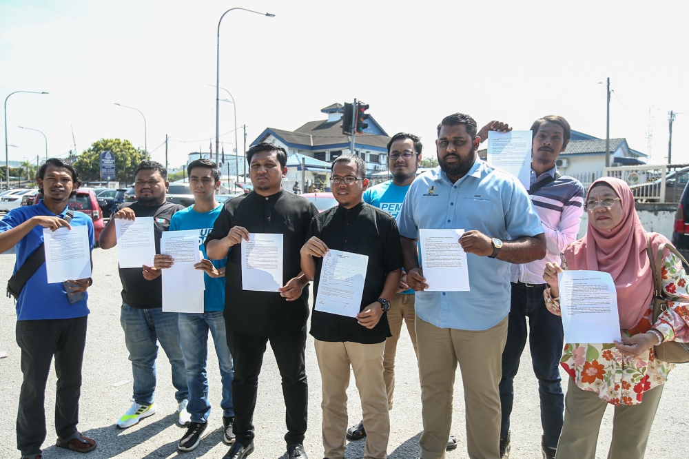Perak PKR Youth chief Zaim Sidqi Zulkifly (fifth left) poses for a group picture outside the Ipoh Police District headquarters March 15, 2023. — Picture by Farhan Najib 