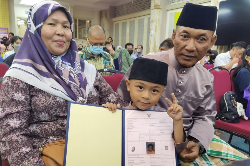 Amar with his parents Awang Musa and Mordiah pose after being given the temporary identification document. — Borneo Post Online pic