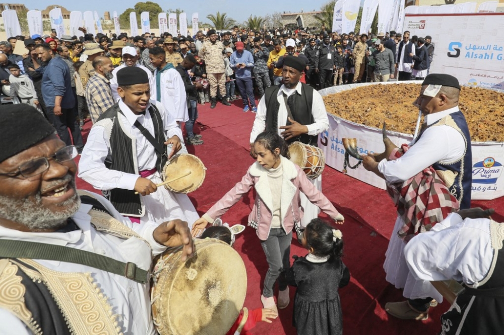 A group of traditional musicians perform around a giant couscous prepared by Libyan chefs on the site of the ancient Roman theatre of Sabratha, about 70 km west of the capital Tripoli,on March 10, 2023. — AFP pic