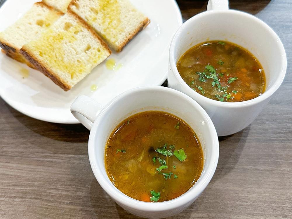 The lunch is served with cups of hot, yummy minestrone soup with focaccia cut into cubes.