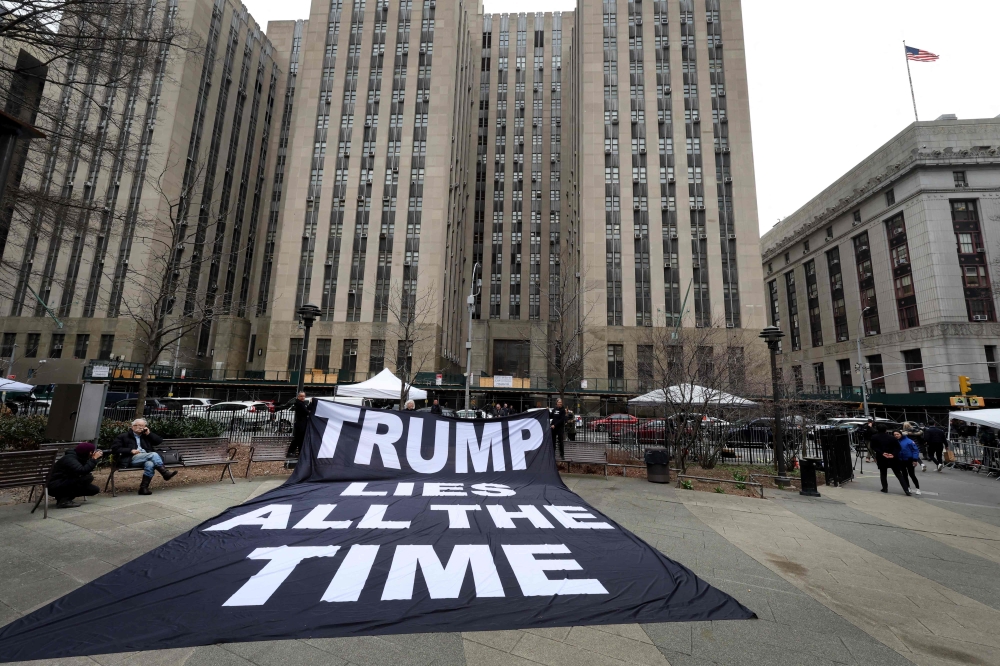 Demonstrators unfurl a banner near Manhattan Criminal Court as the grand jury continues to hear evidence against former President Donald Trump on March 23, 2023 in New York City. — AFP pic