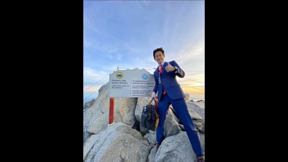 Sada poses on the peak of Mount Kinabalu in his custom-made suit. — Picture via Facebook/Nobutaka Sada