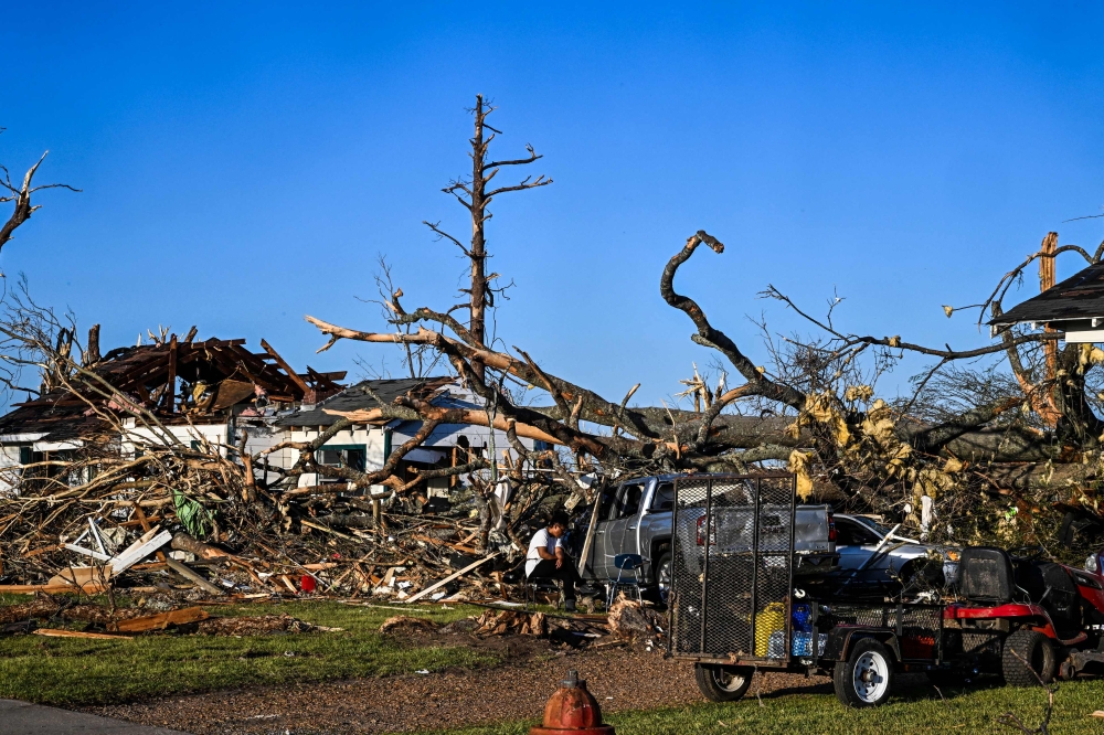 Ramona Brock sits outside the remains of a house and cars entangled in tree limbs in Rolling Fork, Mississippi, after a tornado touched down in the area March 25, 2023. — AFP pic