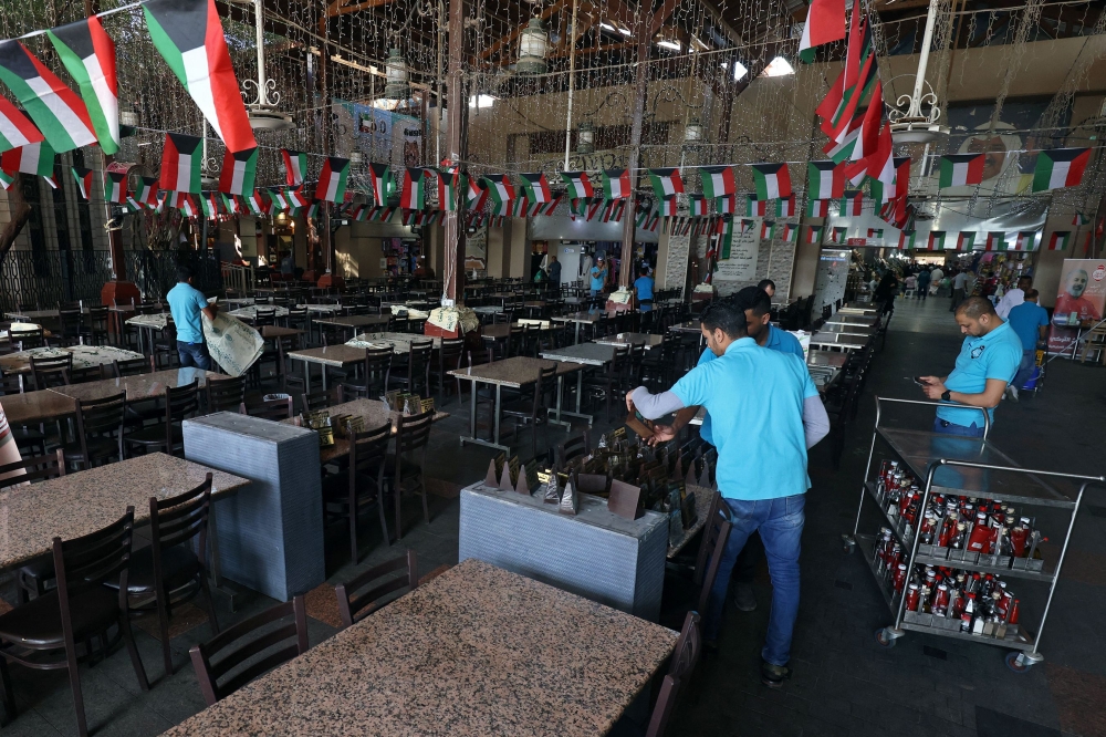 Workers prepare tables at an empty restaurant ahead of iftar on the first day of Islam’s holy fasting month of Ramadan, in Kuwait City on March 23, 2023. — AFP pic