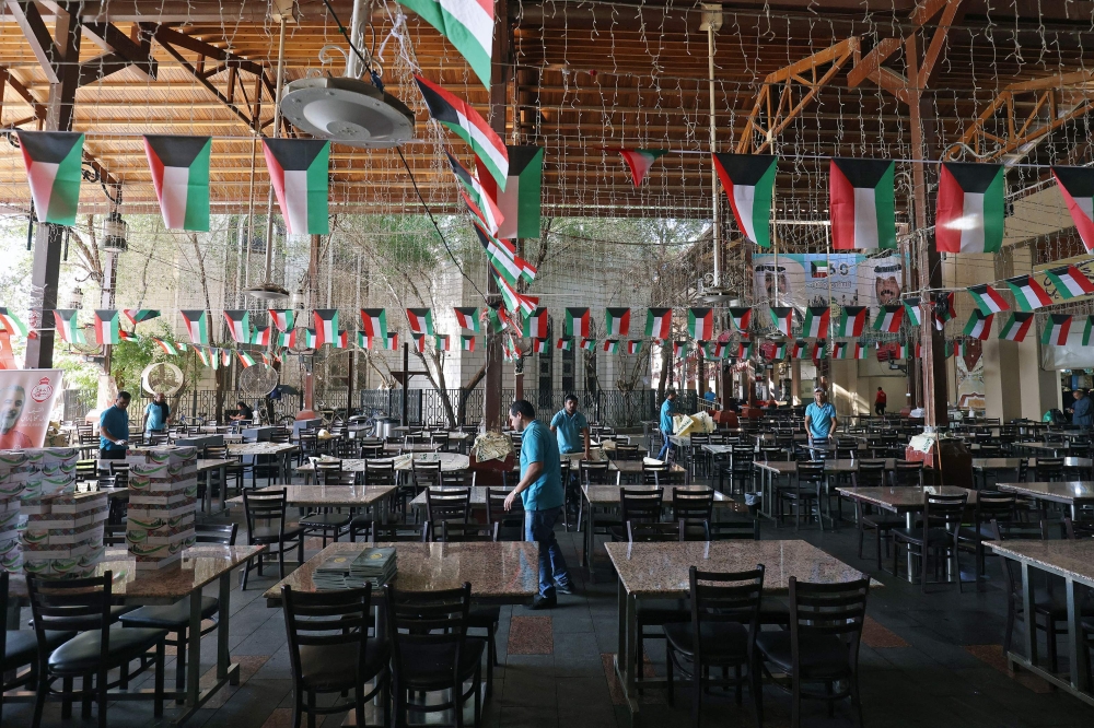Workers prepare tables at an empty restaurant ahead of iftar on the first day of Islam’s holy fasting month of Ramadan, in Kuwait City on March 23, 2023. — AFP pic