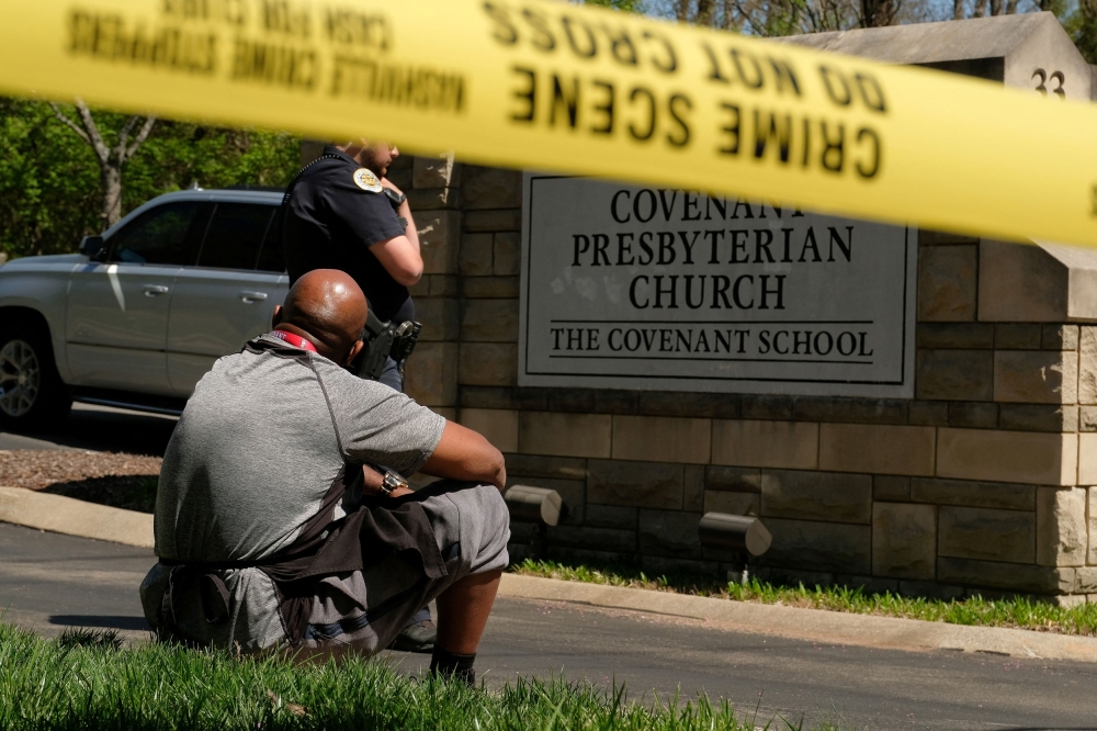 Mario Dennis, one of the kitchen staff at the Covenant School, sits near a police officer after a shooting at the facility in Nashville, Tennessee March 27, 2023. — Reuters pic