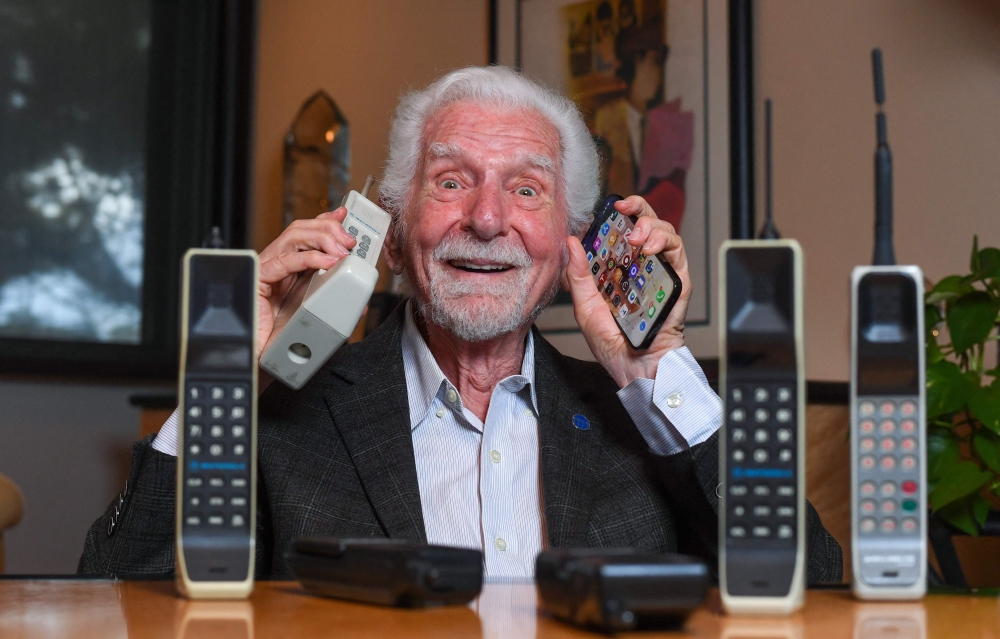 Engineer Martin Cooper holds in his right hand a contemporary copy of the original cell phone he used to make the first cell phone call on April 3, 1973, in Del Mar, California on March 20, 2023. — AFP pic 