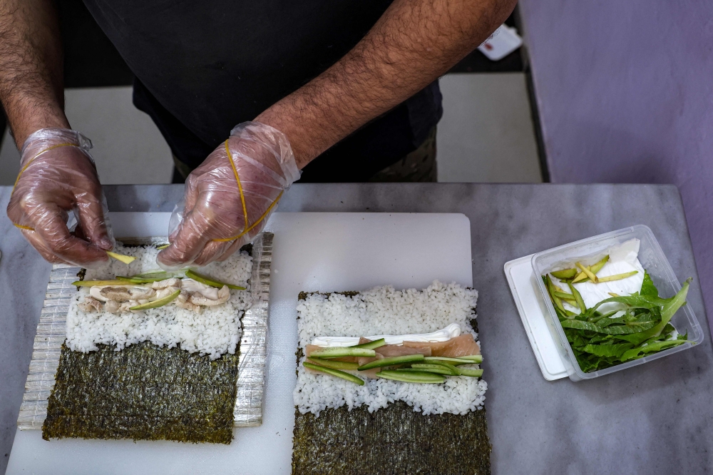 A chef employed by Islam Shakhbanov, a 37-year-old fighter from Russia's Muslim-majority Dagestan republic, cuts sushi rolls at his restaurant in Syria's rebel-held northwestern city of Idlib January 29, 2023 — AFP pic