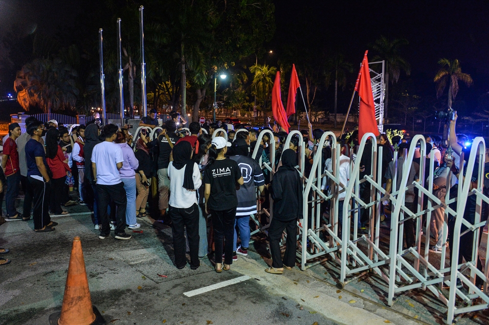 Students and Muda members converge outside UiTM Shah Alam with red flags and armbands after they were blocked from attending the event organised by Muda affiliate Ikatan Mahasiswa Demokratik on March 30, 2023. — Picture by Miera Zulyana