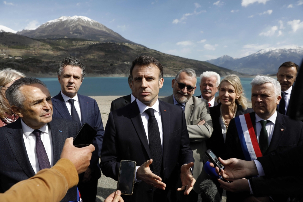 French President Emmanuel Macron speaks to journalists upon his arrival in Savines-Le-Lac, southeastern France, on March 30, 2023. — AFP pic