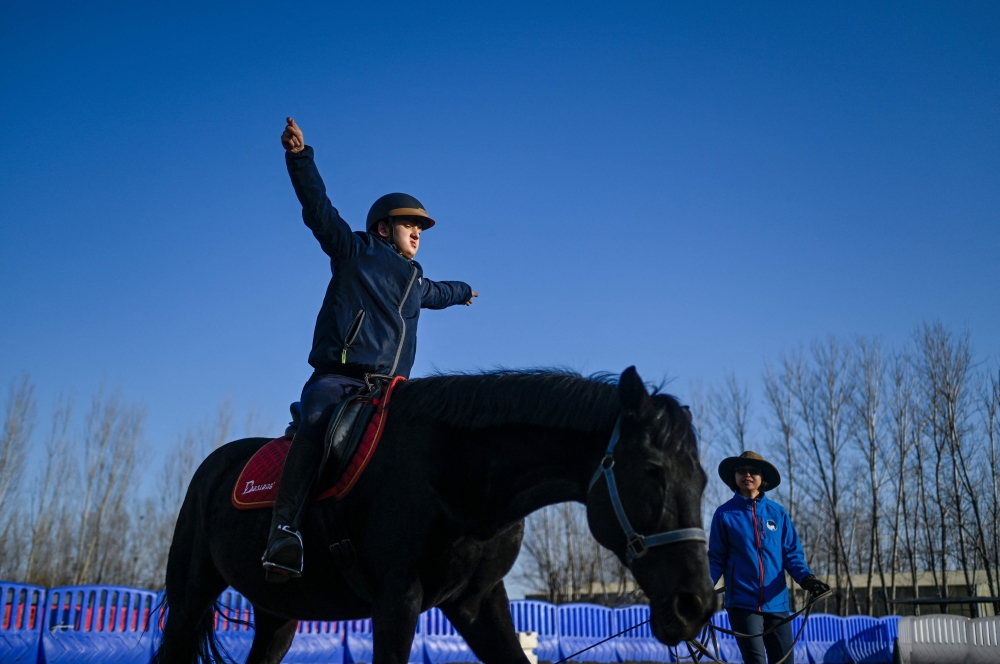 Victor Liu, a 14-year-old Beijinger with visual impairment and autism, practising during a horse riding lesson at a horse club in Beijing March 29, 2023. — AFP pic