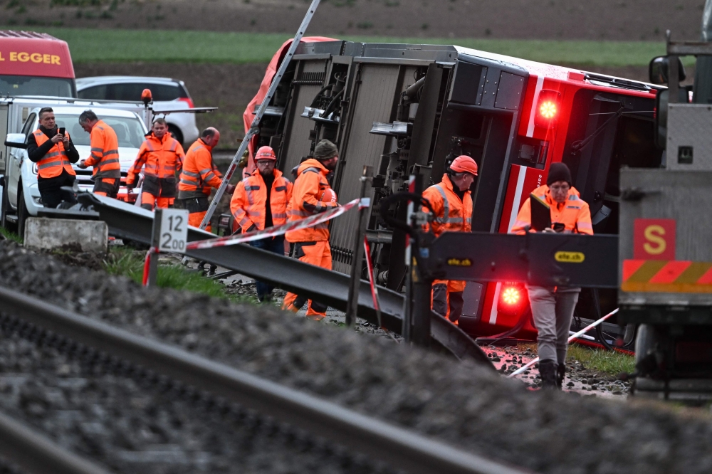 Train staffs inspect at the site of a train derailment near lakeside town of Luscherz, northwest of the capital Bern March 31, 2023. — AFP pic
