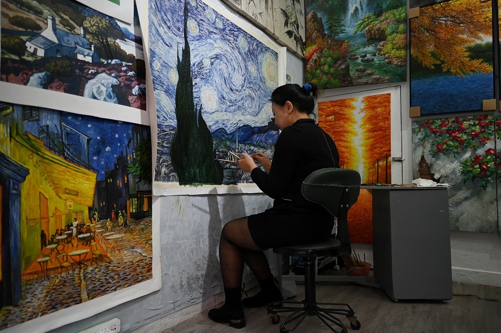 An artist painting a Vincent Van Gogh replica in a studio at Dafen village, in Shenzhen, in China’s southern Guangdong province. — AFP pic