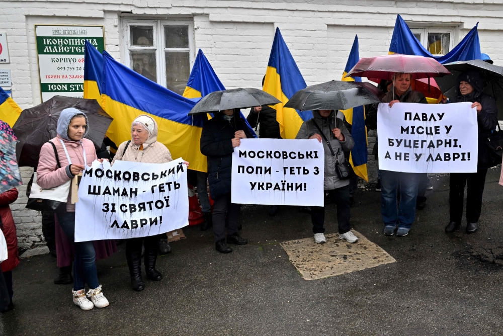 People hold placards reading ‘Moscow priests get away  from Ukraine!’ and ‘Moscow shaman get away  from holy Lavra!’ as they rally at the entrance to the Kyiv-Pechersk Lavra in Kyiv on March 28, 2023. — AFP pic