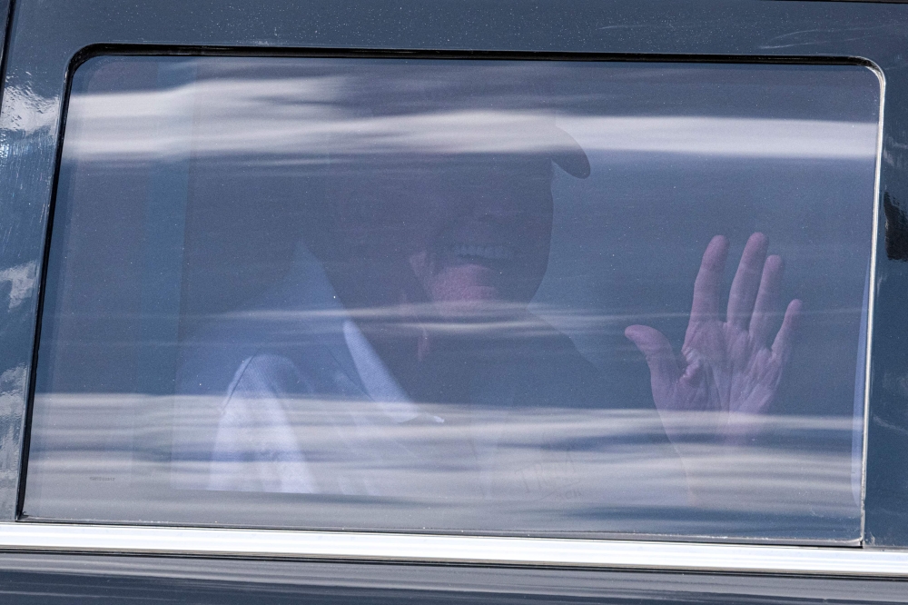 Former US President Donald Trump sits in the rear of his limousine as he departs Trump International Golf Club in Palm Beach, Florida, on April 2, 2023. — AFP pic