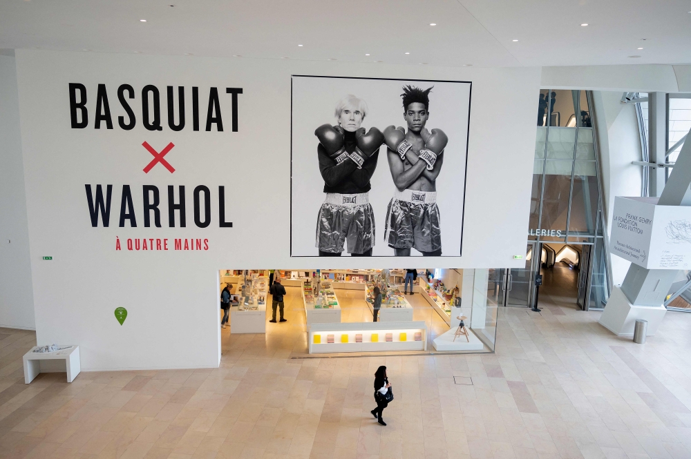 A visitor walks past a black and white photograph made in 1985 by US Michael Halsband, depicting portraits of US Neo-expressionism artist Jean-Michel Basquiat (right) (1960-1988) and US artist, film director and producer Andy Warhol (left) (1928-1987), during a preview of the exhibition 