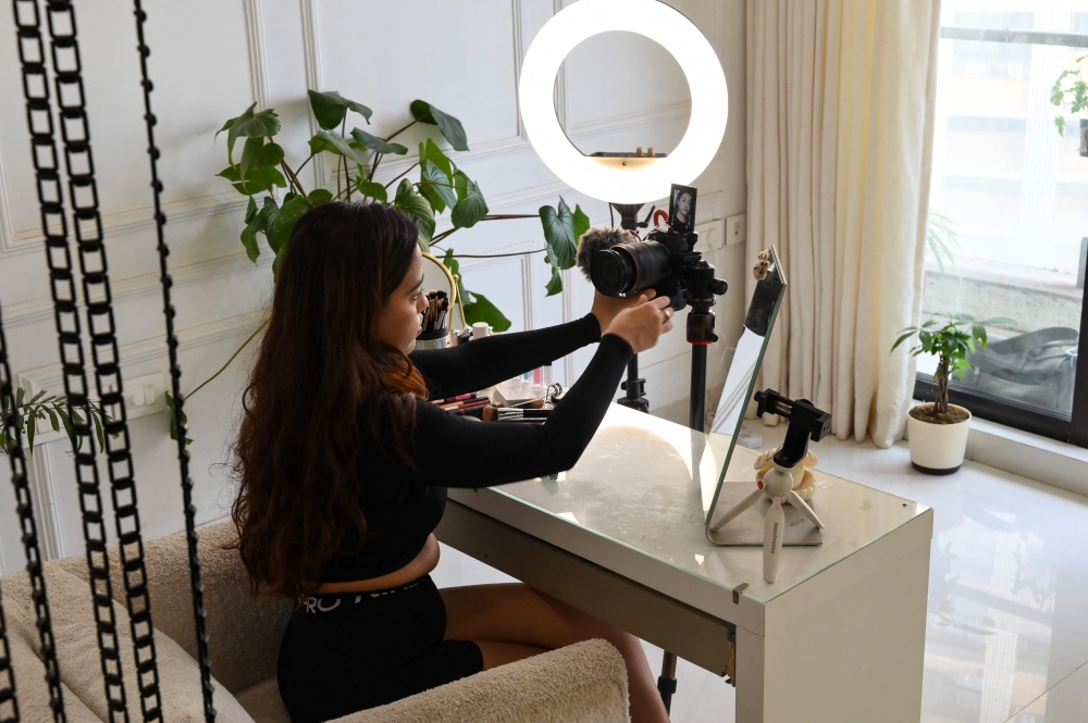 In this photo taken on March 16, 2023, social media beauty and lifestyle influencer Debasree Banerjee sets up her camera and light before live streaming on her YouTube channel in Mumbai. — AFP pic