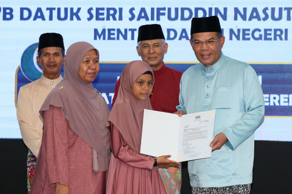 Minister of Home Affairs (KDN) Datuk Seri Saifuddin Nasution Ismail (right) handing over citizenship decision letters to selected recipients during KDN Madani Iftar at the Terengganu Police Contingent Headquarters (IPK) April 5, 2023. — Bernama pic