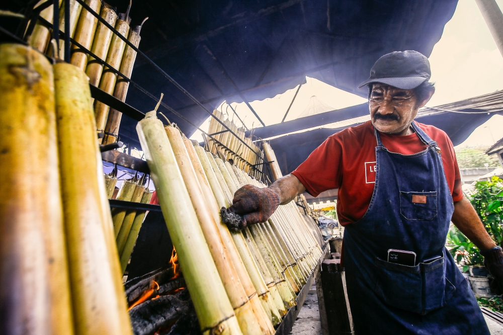 Mohd Arifin Zakaria, 64 tending to the lemang being cooked at his stall in Greenwood, Batu Caves, March 31, 2023. — Picture by Hari Anggara