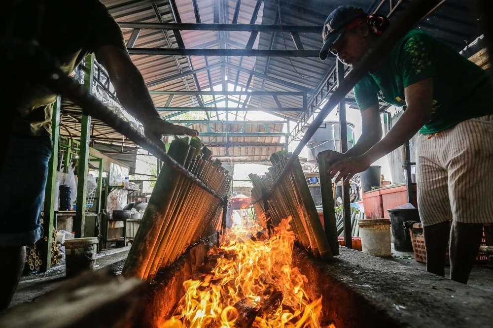 Workers preparing their customer`s order as they fire up almost a hundred Lemang tubes at Pak Ali Lemang Asli stall in Ulu Klang. — Picture by Sayuti Zainudin