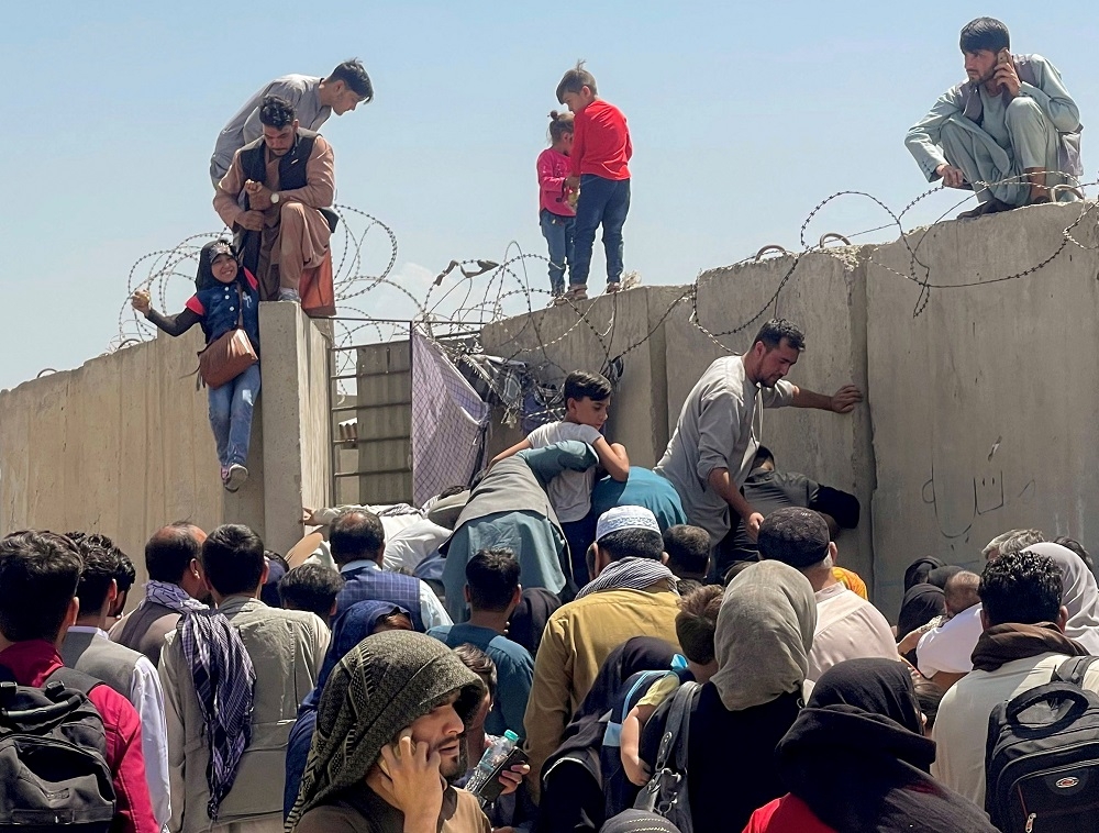 File picture showing a man pulling a girl to get inside Hamid Karzai International Airport in Kabul August 16, 2021. — Reuters pic