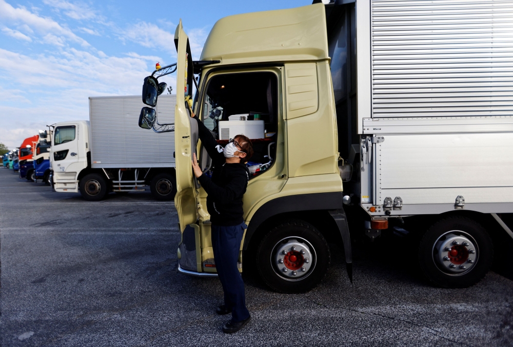 Truck driver Yuichi Tomita cleans his 10-tonne truck as he takes a break during his delivery work at a parking area along the highway in Chiba, east of Tokyo, Japan April 6, 2023. — Reuters pic